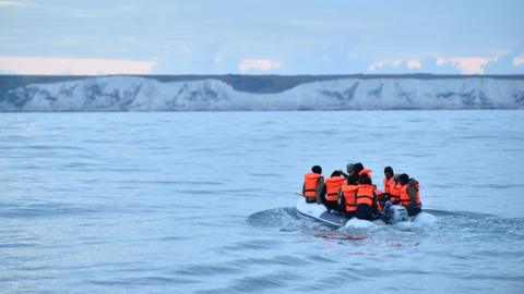 Migrants in a dinghy sail in the Channel toward the south coast of England