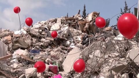 Red balloons on the rubble of a destroyed building in Turkey