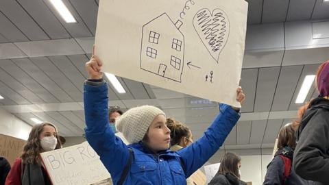 A boy holds a sign for refugees