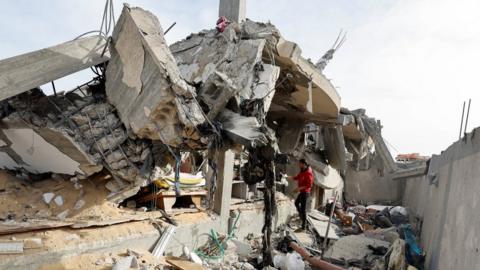 A Palestinian man inspects a building destroyed in a reported Israeli air strike in Rafah, in the southern Gaza Strip (26 March 2024)
