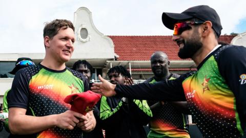 Zimbabwe's Gary Ballance (L) receives his first ODI cap from Sikandar Raza ahead of the first one day international cricket match between Zimbabwe and Ireland at the Harare Sports Club in Harare