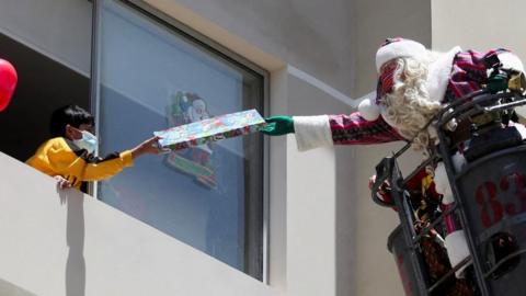 Santa delivers a present to a child from a firefighter ladder