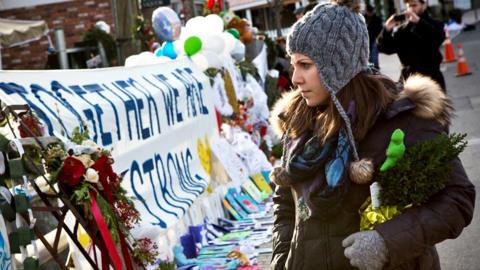 A woman looks at a memorial for those killed in the school shooting at Sandy Hook Elementary School, on 24 December 2012 in Newtown, Connecticut
