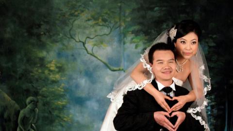 A Chinese man and woman a posing for a wedding photo