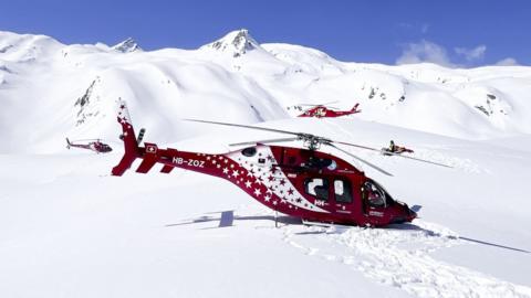 Rescue helicopter on the mountain landing site of the Petit Combin summit in Valais, Switzerland