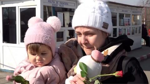 A mother receives flowers at the border in Romania