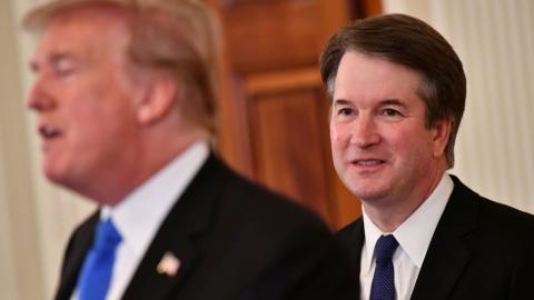 Brett Kavanaugh watches as Donald Trump introduces him at the White House.