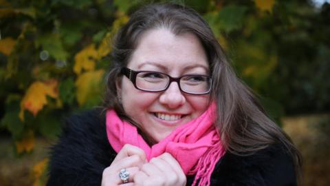 Caroline Walker smiling against a leafy background