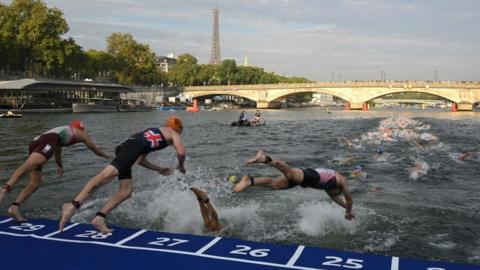 Triathlon athletes dive into The Seine river with the Eiffel Tower in the background