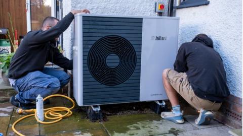 Technicians service an air source heat pump
