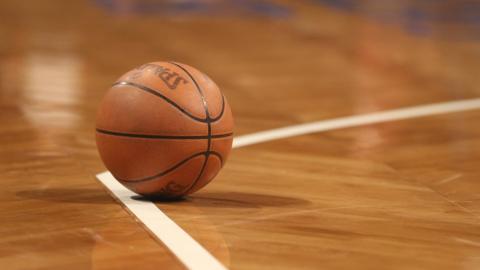A basketball sits on the corner of a line on the court
