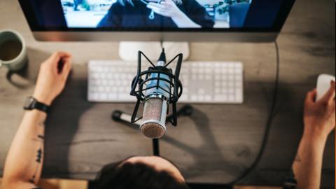 A person with a microphone editing video at home