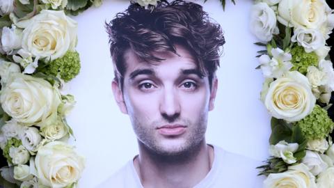 A floral tribute to Tom Parker, with his photo and a border of white roses