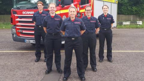 Female fire fighters standing in front of a fire engine