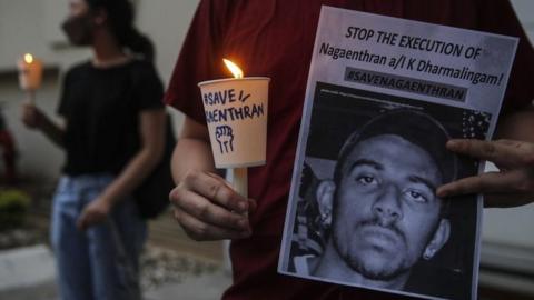 An activist holds a placard outside the Singaporean embassy in Kuala Lumpur, Malaysia, on 8 November 2021