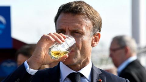 French President Emmanuel Macron drinks beer as he concludes a two-day government meeting in the northern German port city of Hamburg in October 2023