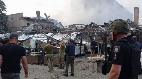 Ukrainian rescuers and policemen work on the site of a rocket hit in downtown Kramatorsk