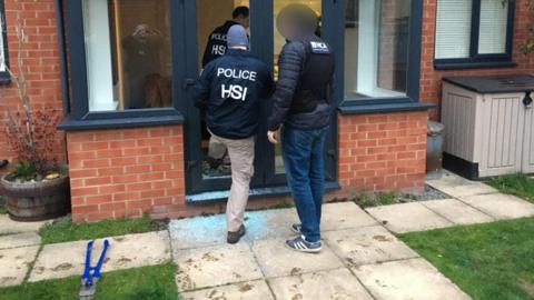Police entering a property as part of an investigation into a gang selling large quantities of ecstasy around the world on the dark web