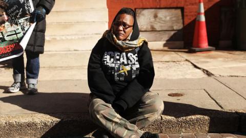 Erricka Bridgeford sitting on the sidewalk where her son was killed