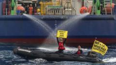 Manifestantes de Greenpeace en una embarcación sostienen pancartas