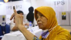 Kusmiasih Kaswih (84) lansia asal Bandung menunjukkan jari tercelup tinta usai menyalurkan suara di World Trade Center (WTC) Kuala Lumpur, Minggu (11/2/2024).