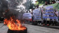 Massa Forum Masyarakat Pemuda Mahasiswa Timur Cinta NKRI membakar ban dan membawa poster saat aksi unjuk rasa di Kantor Indonesia Corruption Watch (ICW), Jakarta, Senin (26/2).