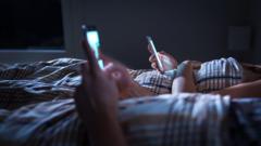 Deux personnes allongées dans un lit utilisant des téléphones portables