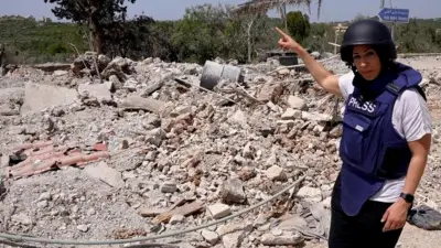 Carine Torbey in bulletproof vest and helmet pointing at debris