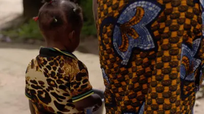 A young girl standing next to her mother