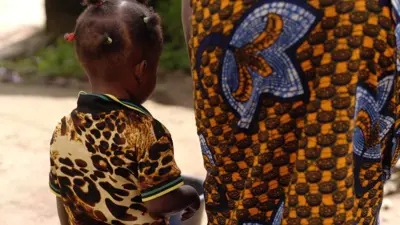 A young girl standing next to her mother