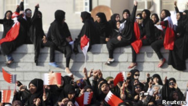 Бахрейнские женщины в чадре сидят на парапете здания