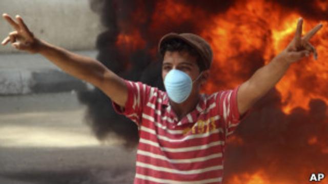 Египетский подросток на фоне пламени во время протестов в Каире
