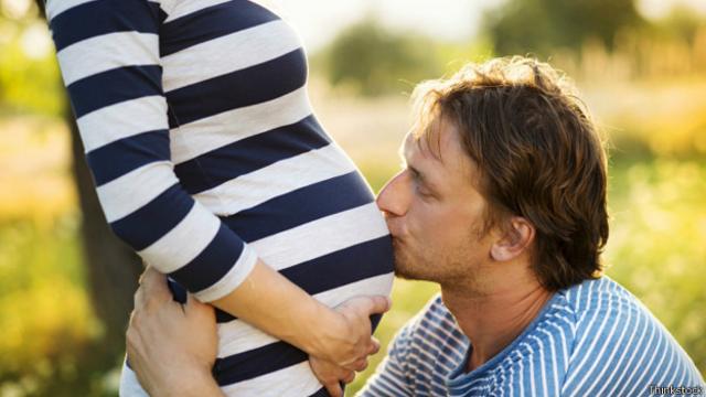 Мужчина целует беременную женщину в живот