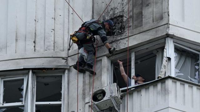 A specialist inspects the damaged facade of a multi-storey apartment building after a reported drone attack in Moscow on May 30, 2023