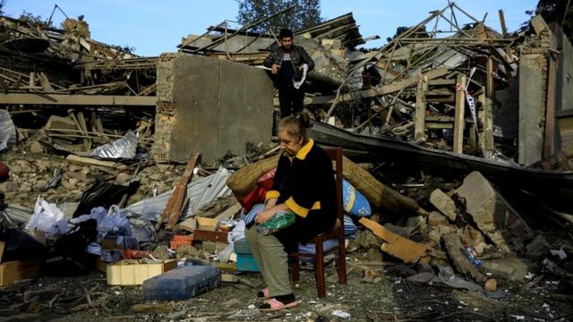 Жительница Гянджи сидит у разрушенного дома