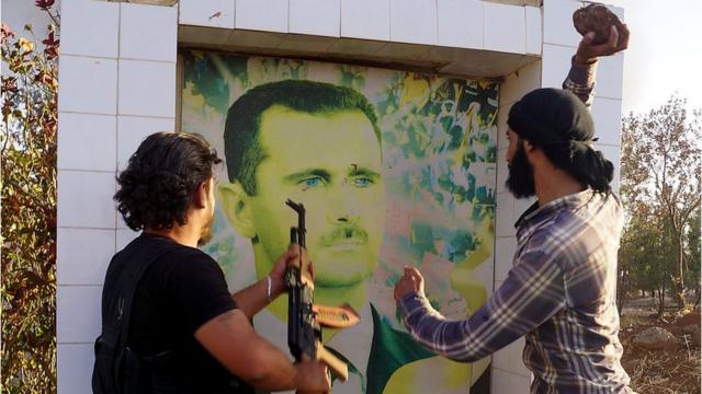 Syrian opposition fighters damage a portrait of Bashar al-Assad in Deraa (file photo)