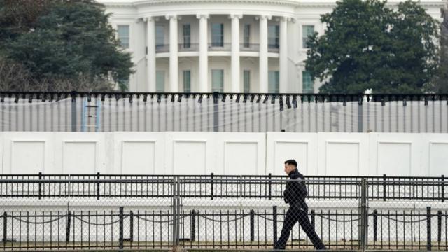 A member of the Secret Service walks along security fence installed around the White House