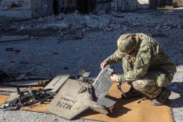Украинский военный специалист исследует обломки иранского дрона "Шахед-136", атаковавшего инфраструктурный объект в Харькове 6 октября 2022 года