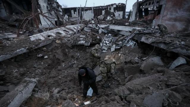 Полиция и следователи осматривают воронку в промышленной зоне после российского ракетного удара в Харькове, нанесенного накануне, 15 декабря