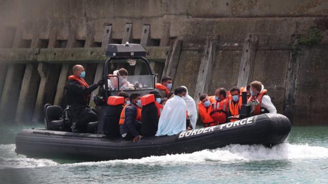 Британская береговая охрана и мигранты входят в порт Дувра