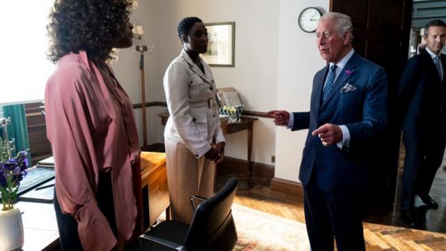 Чернокожая актриса Лашана Линч в роли агента 007 и ее коллега Наоми Харрис (Манипенни) встречаются с принцем Чарльзом во время съемок последнего на сегодняшний день фильма бондинианы "Не время умирать". 20 июня 2019 г.