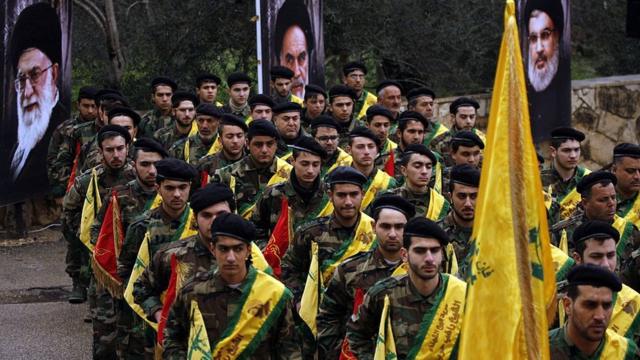 Боевики "Хезболлы" маршируют перед портретами лидеров группировки и Ирана