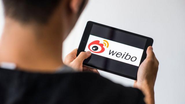 Человек с планшетом с логотипом Weibo