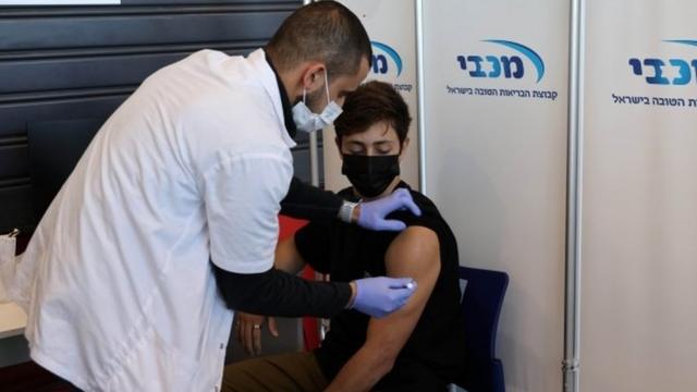 A teenager receives a vaccination against the coronavirus disease