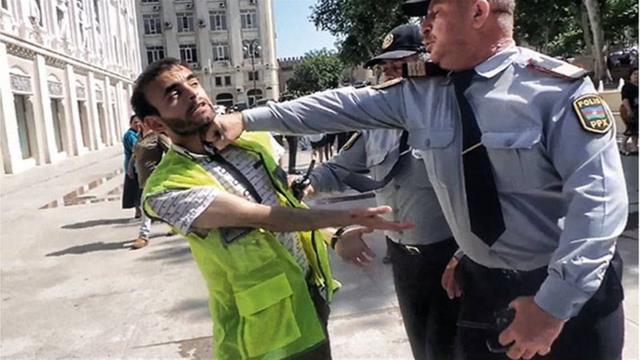 Полицейский бьет в челюсть журналиста в светоотражающем жилете