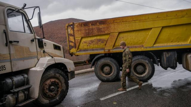 Сотрудник миротворческого отряда ООН у баррикады на дороге в Косово