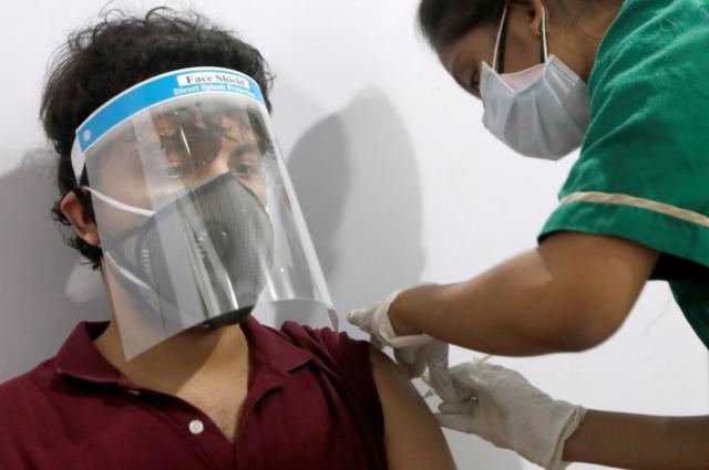 молодому человеку, жителю Мумбаи, ставят прививку