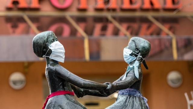 Памятник с двумя танцующими девочками, на лица которых надеты маски. Германия