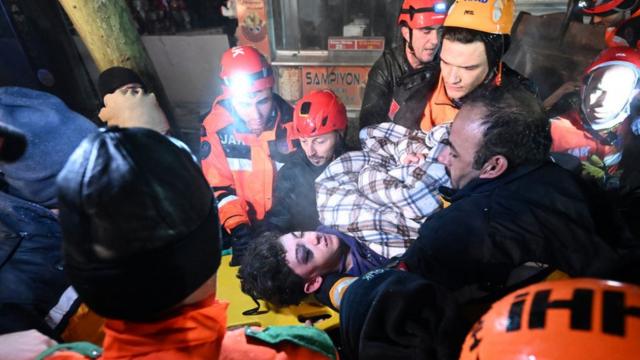 Спасатели выносят из-под обломков спасенного мальчика