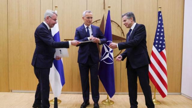 Министр иностранных дел Финляндии Пекка Хаависто (слева) передает документы о вступлении Финляндии в НАТО государственному секретарю США Энтони Блинкену (справа) и генеральному секретарю НАТО Йенсу Столтенбергу